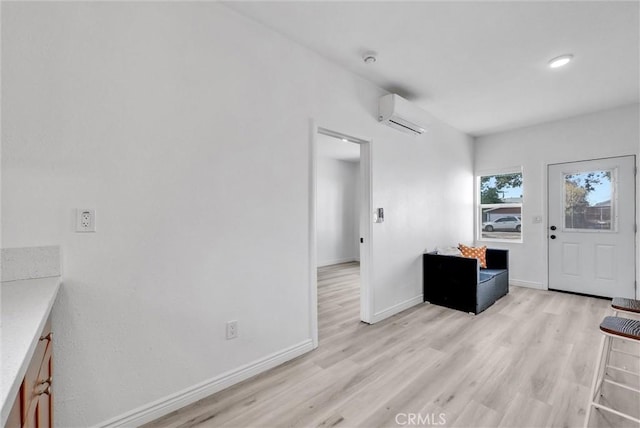 foyer with a wall unit AC and light hardwood / wood-style flooring