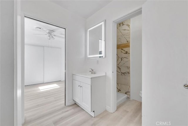 bathroom with walk in shower, vanity, ceiling fan, wood-type flooring, and toilet