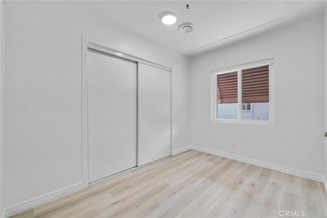 unfurnished bedroom with light wood-type flooring and a closet