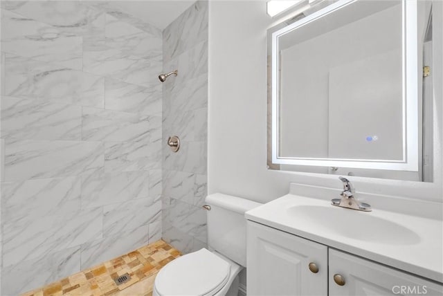 bathroom with a tile shower, vanity, and toilet