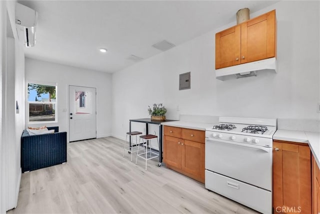 kitchen with white gas range, light hardwood / wood-style flooring, and electric panel