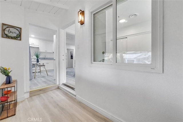 hallway with beamed ceiling, wood ceiling, sink, and light hardwood / wood-style flooring