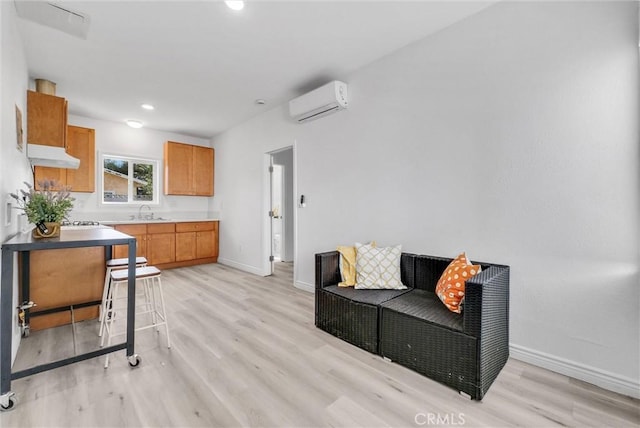 living room featuring a wall mounted air conditioner, light hardwood / wood-style floors, and sink