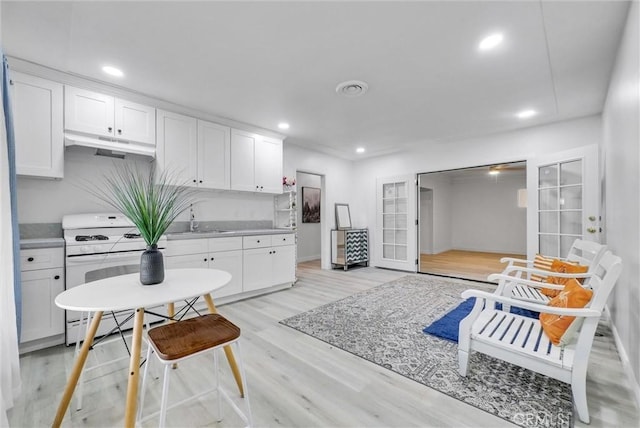 kitchen with french doors, white cabinets, sink, light hardwood / wood-style floors, and white range oven