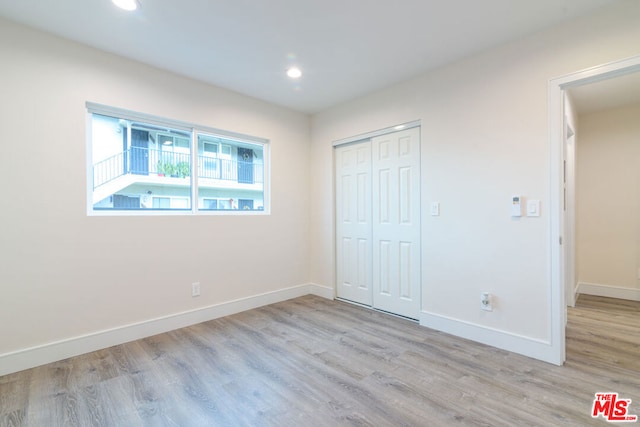 unfurnished bedroom with light hardwood / wood-style flooring and a closet