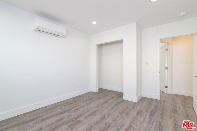 unfurnished bedroom featuring light hardwood / wood-style floors and a wall unit AC