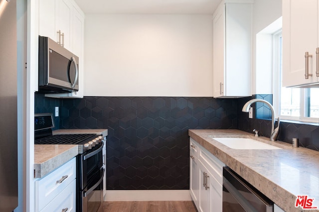 kitchen with light hardwood / wood-style floors, white cabinetry, and appliances with stainless steel finishes