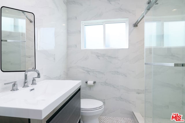 bathroom with tiled shower, vanity, toilet, and tile walls