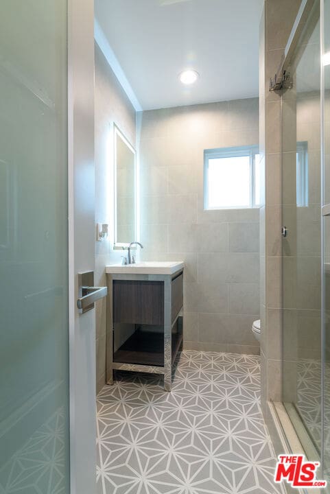 bathroom featuring tile patterned floors, vanity, toilet, and tiled shower