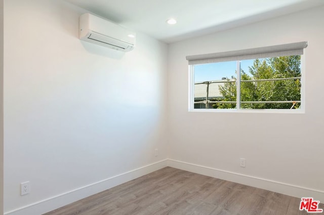 spare room with a wall unit AC and light hardwood / wood-style floors