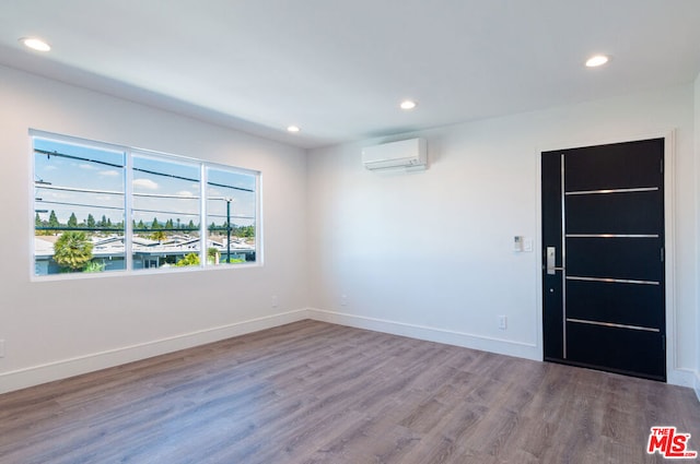 empty room featuring a wall mounted air conditioner and hardwood / wood-style floors