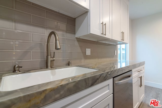 kitchen with tasteful backsplash, light stone counters, sink, hardwood / wood-style flooring, and white cabinets