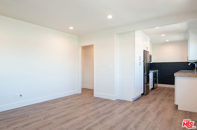 kitchen with white cabinetry, light hardwood / wood-style flooring, appliances with stainless steel finishes, and sink