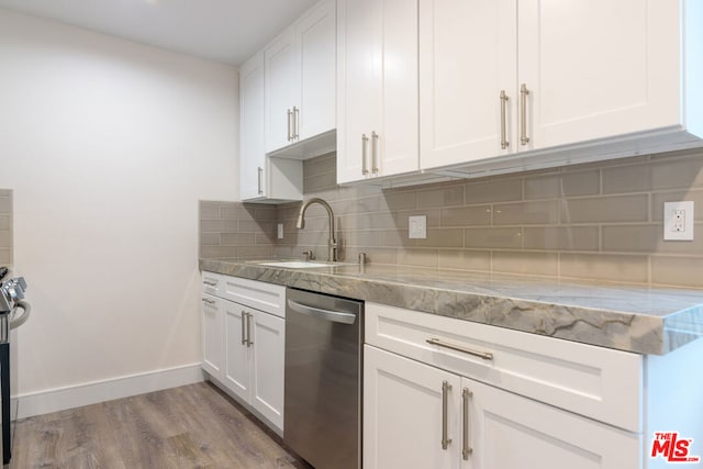 kitchen with light stone countertops, white cabinetry, sink, and light hardwood / wood-style flooring