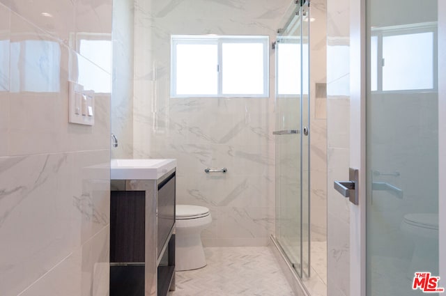 bathroom featuring walk in shower, vanity, a healthy amount of sunlight, and toilet