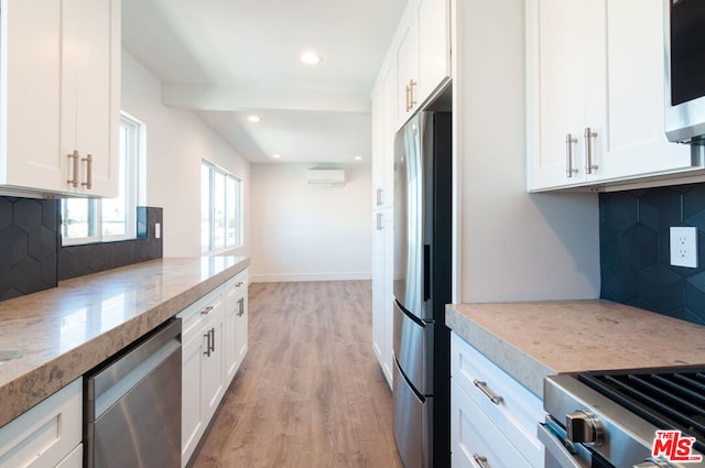 kitchen featuring stainless steel appliances, white cabinetry, and tasteful backsplash