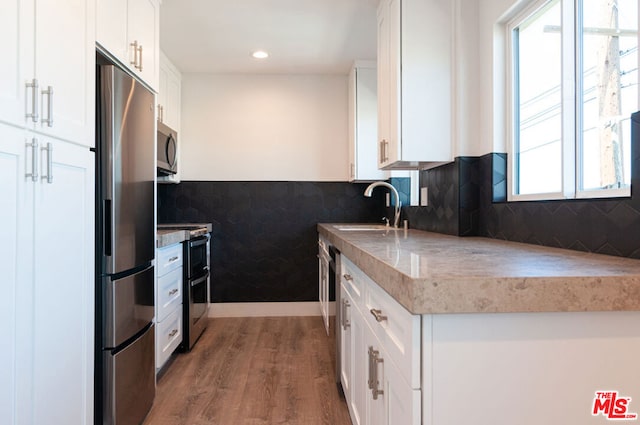 kitchen with white cabinets, appliances with stainless steel finishes, a wealth of natural light, and hardwood / wood-style floors