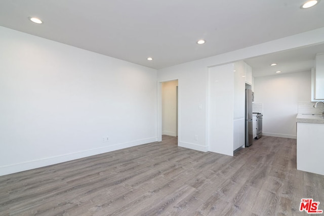 unfurnished room featuring light wood-type flooring and sink