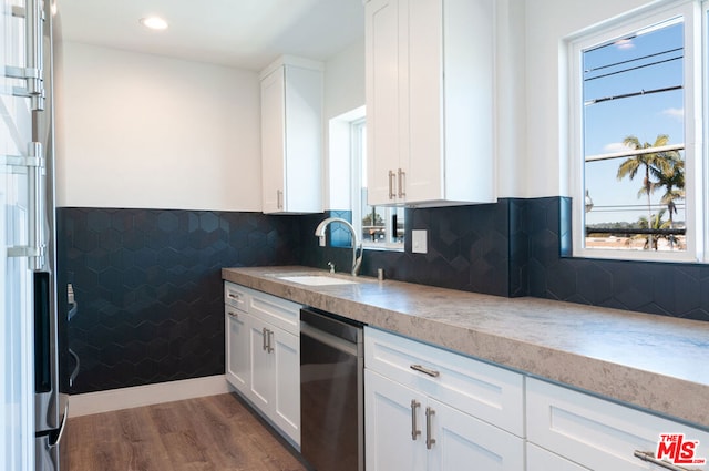 kitchen featuring white cabinets, stainless steel dishwasher, sink, and dark wood-type flooring