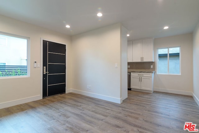 interior space featuring white cabinets, light hardwood / wood-style floors, and a healthy amount of sunlight