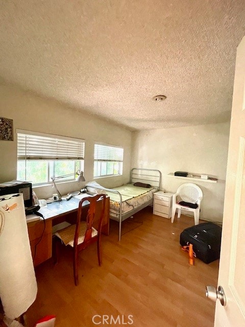 bedroom with built in desk, light hardwood / wood-style floors, and a textured ceiling