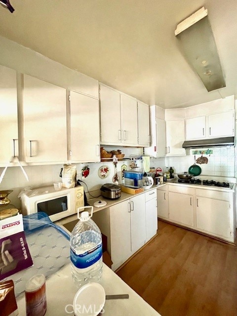 kitchen featuring white cabinetry, hardwood / wood-style flooring, tasteful backsplash, and stainless steel gas cooktop