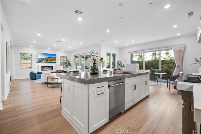 kitchen with an island with sink, white cabinetry, a healthy amount of sunlight, and sink