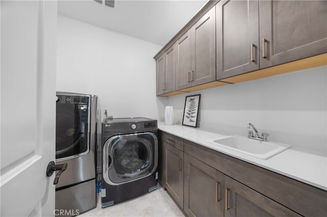 washroom with washing machine and clothes dryer, sink, and cabinets