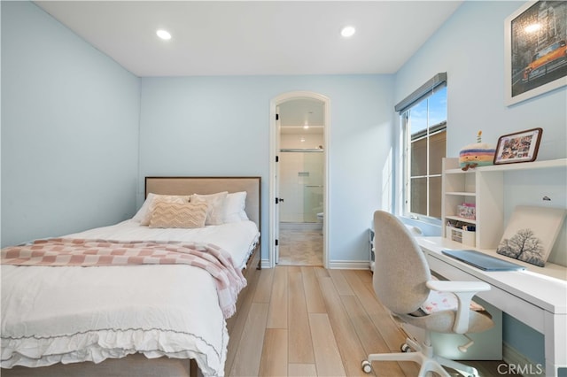 bedroom with connected bathroom and light hardwood / wood-style flooring