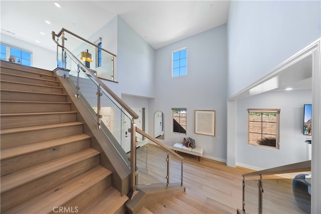 staircase with wood-type flooring and a high ceiling