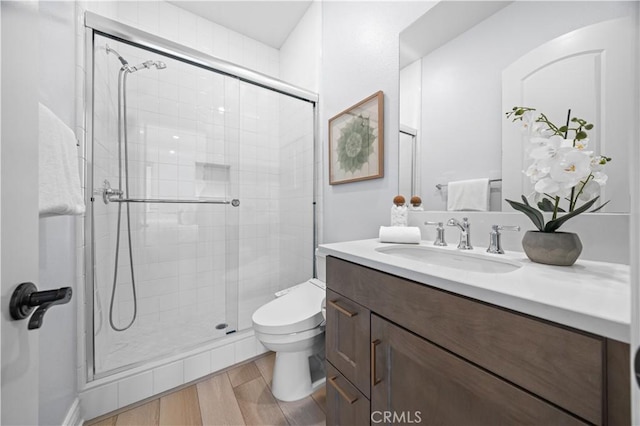 bathroom with vanity, hardwood / wood-style flooring, toilet, and a shower with door