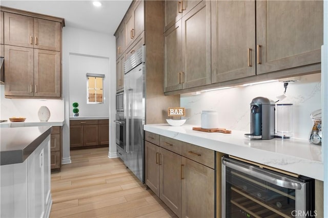 kitchen with light wood-type flooring, tasteful backsplash, and beverage cooler