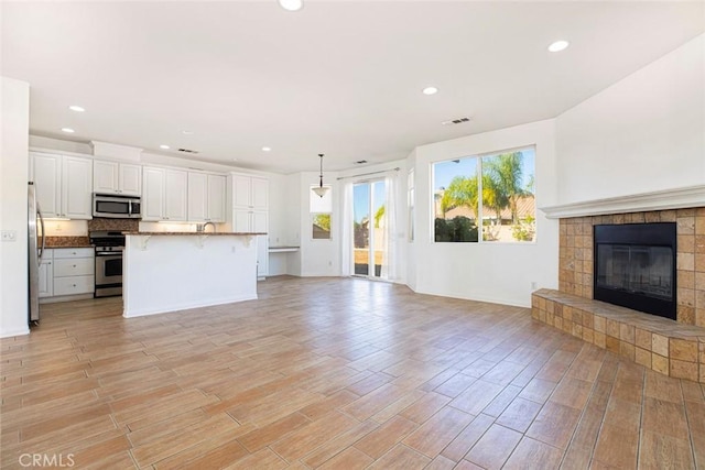 unfurnished living room featuring light hardwood / wood-style floors and a tiled fireplace