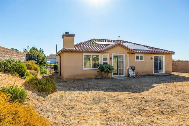 rear view of property featuring solar panels