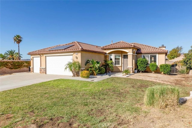 mediterranean / spanish-style home with solar panels, a garage, and a front yard