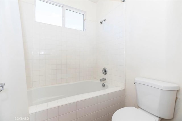 bathroom featuring tiled shower / bath combo and toilet