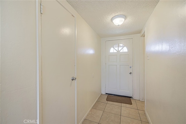 entryway with light tile patterned flooring and a textured ceiling