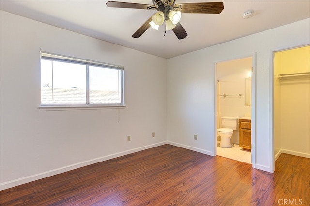 unfurnished bedroom with ceiling fan, a spacious closet, dark hardwood / wood-style floors, ensuite bathroom, and a closet