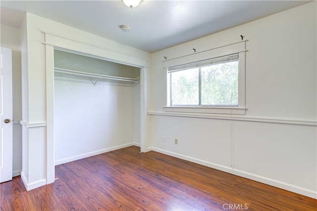 unfurnished bedroom featuring a closet and dark hardwood / wood-style flooring