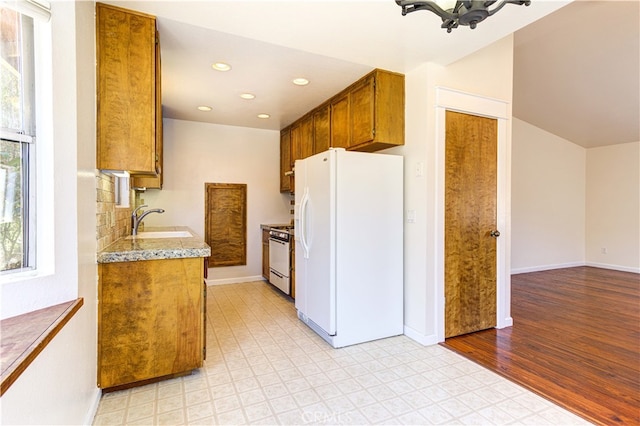 kitchen with sink, light wood-type flooring, and white appliances