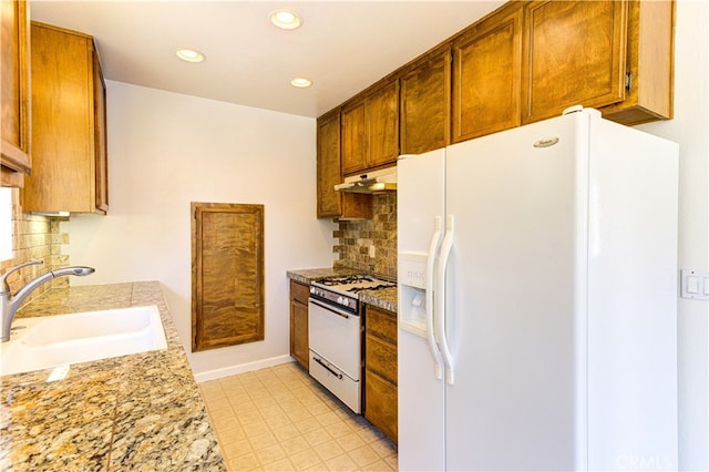 kitchen with tasteful backsplash, sink, light stone counters, and white appliances