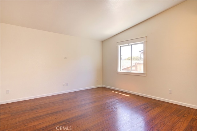 unfurnished room featuring vaulted ceiling and dark hardwood / wood-style floors