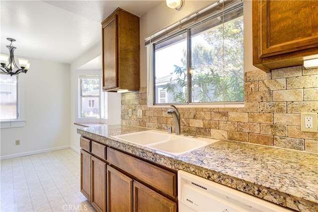 kitchen with decorative backsplash, hanging light fixtures, white dishwasher, sink, and a chandelier