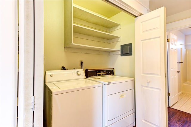 laundry area featuring electric panel, independent washer and dryer, and wood-type flooring