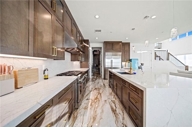 kitchen featuring light stone countertops, decorative backsplash, high end appliances, sink, and pendant lighting