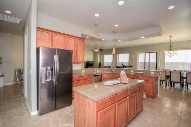 kitchen with kitchen peninsula, appliances with stainless steel finishes, sink, a center island, and hanging light fixtures