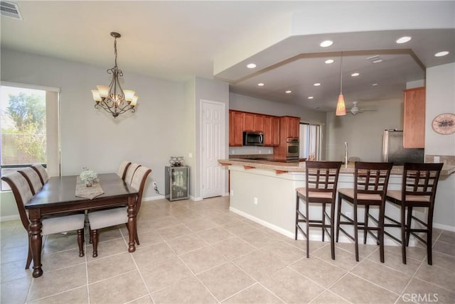 kitchen featuring ceiling fan with notable chandelier, light tile patterned flooring, kitchen peninsula, and stainless steel appliances