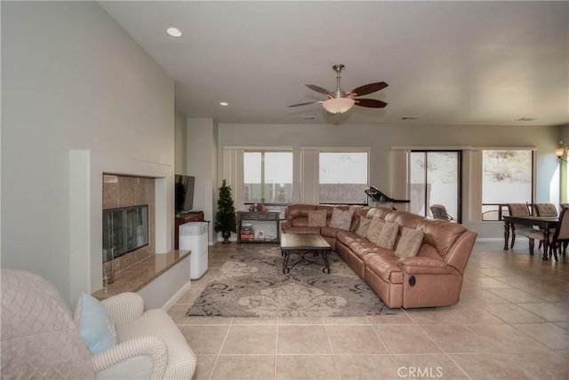 living room featuring ceiling fan, light tile patterned floors, and a tile fireplace