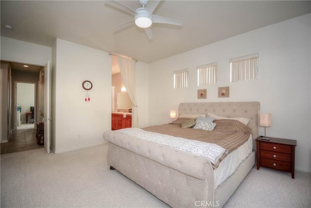 bedroom with ceiling fan, light colored carpet, and ensuite bathroom