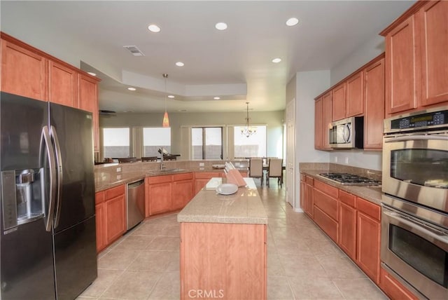 kitchen featuring pendant lighting, a center island, sink, appliances with stainless steel finishes, and a notable chandelier